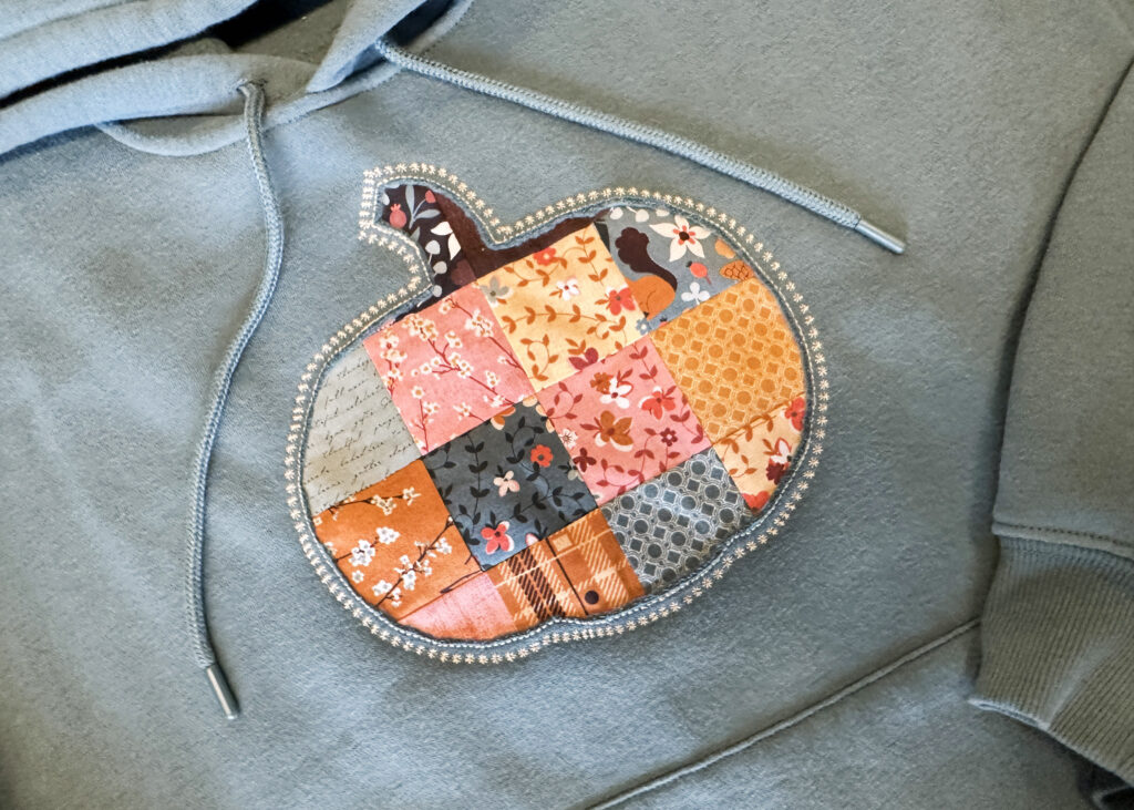 Completed patchwork pumpkin appliqué sweatshirt made with NECCHI NE210 sewing machine